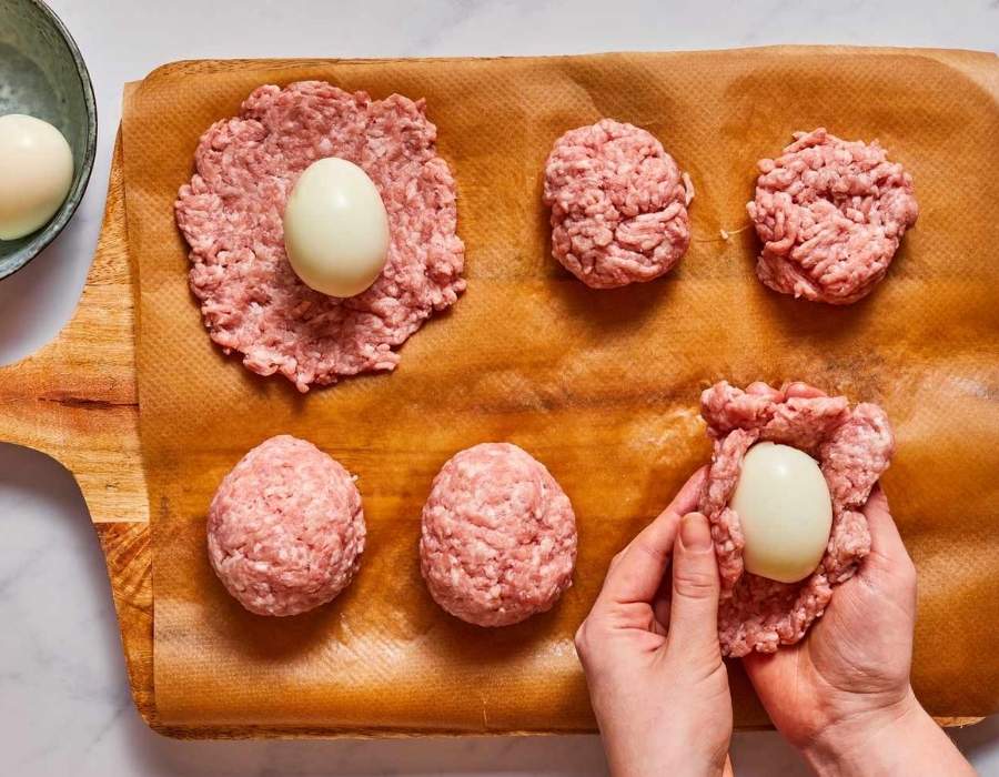 Wrap each boiled egg with sausage evenly around it.n